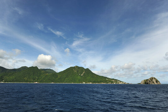 Dominica, Roseau, rock which southern tip of the island and lush green hills in background