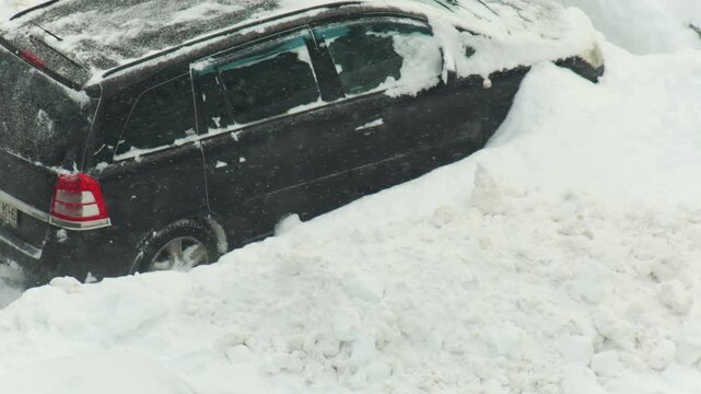 Dark vehicle attempts movement in deep fresh snow, wheels spinning, snow flying, difficult winter driving conditions, problem with traction, slow mo