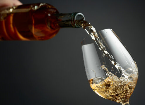 Pouring white wine from a bottle into a glass.