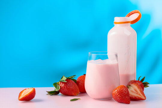 Strawberry milkshake smoothie and fresh berries on a colorful background.