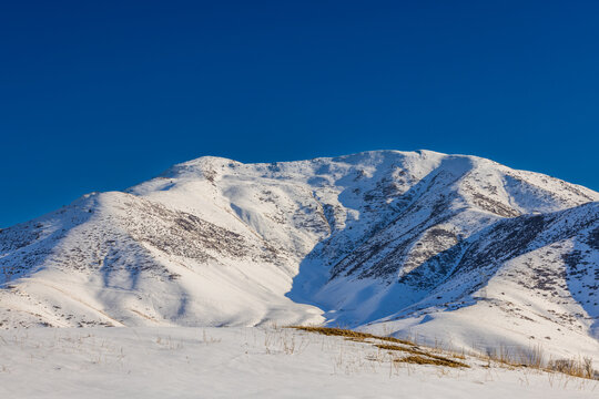 Snow-Covered Mountains Under Clear Blue Sky in Kyrgyzstan