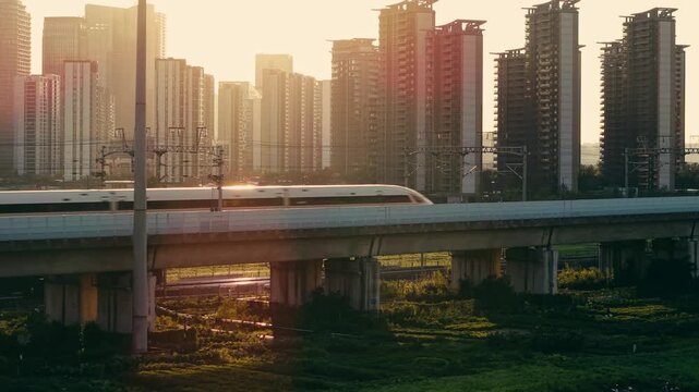 Aerial view of a high speed train travels on an elevated track past tall apartment buildings in China