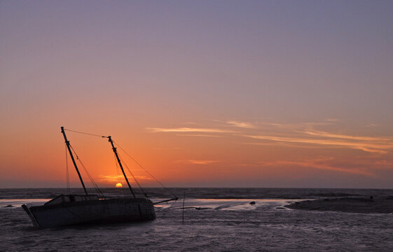 Madagascar, Morondava, Fisherman boat at sea at low tide at sunset