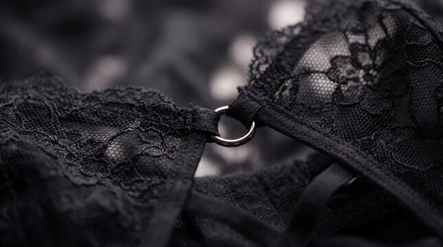 Black lace lingerie closeup showing floral fabric texture straps metal ring detail creating elegant intimate fashion concept for underwear design sensual style feminine apparel retail