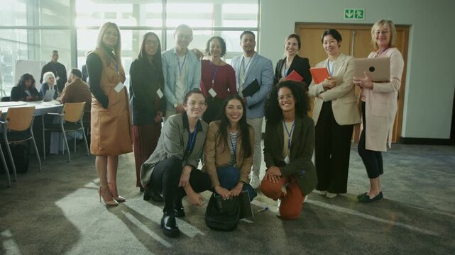 A group of smiling business professionals pose for a photo at a large conference or event. They represent a collaborative and successful team, enjoying their time together.