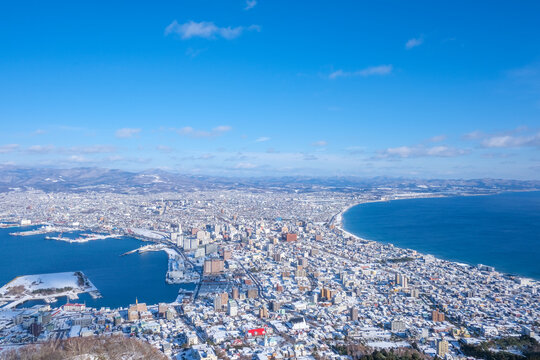 Panoramic high-angle view of snow-covered Hakodate city and surrounding bays from Mount Hakodate in Hokkaido, Japan during winter