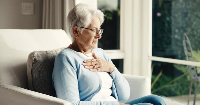 Senior, woman and thinking in home with chest pain, acid reflux or heart attack symptoms of angina. Retirement, old person or discomfort on sofa for heartburn, lung infection or respiratory condition