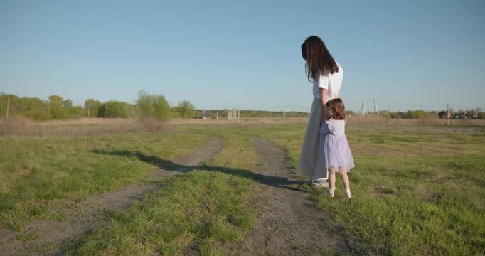 Young mother with child daughter spend time playing enjoying nature. 4K 10-bit
