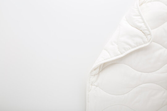 New clean white fibre duvet on light gray table background. Closeup. Empty place for text. Flat lay. Top down view.