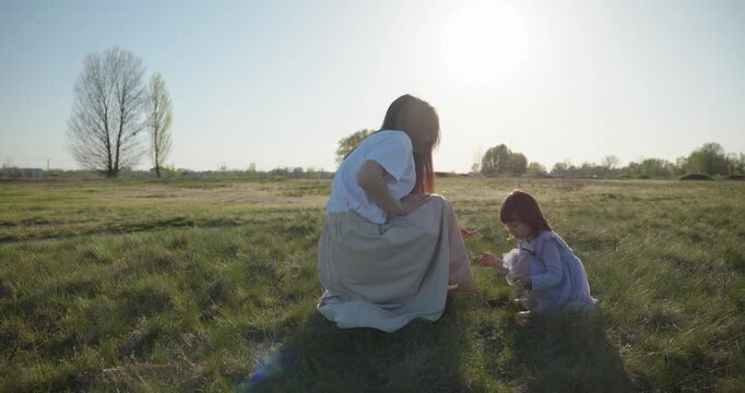 Young mother with child daughter spend time playing enjoying nature. 4K 10-bit