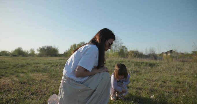 Young mother with child daughter spend time playing enjoying nature. 4K 10-bit