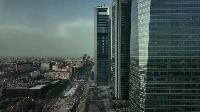 Modern glass office towers dominate an elevated view across Madrid's financial district and surrounding city.
