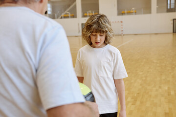 Naklejka premium Senior man and teenage boy talking together while spending time together at an indoor gym