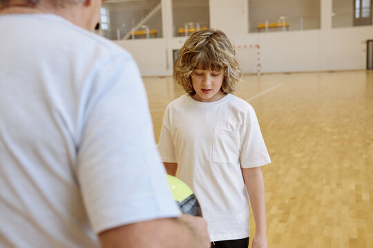 Senior man and teenage boy talking together while spending time together at an indoor gym