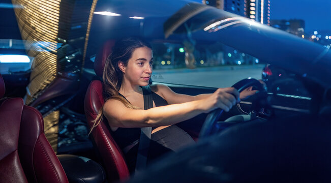 Serious pregnant woman keeping both hands on the steering wheel while driving at night