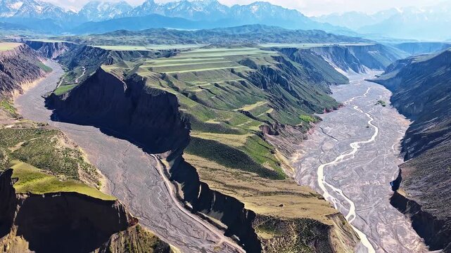 Aerial view of braided river channels flowing through colorful eroded cliffs in Anjihai Grand Canyon, Xinjiang, China.