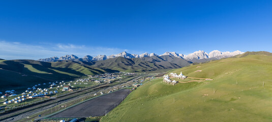 Naklejka premium Panoramic View of Maya Snow Mountain with Grassland and Tibetan Tent Camps at Morning