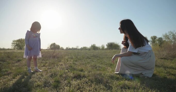 Young mother with child daughter spend time playing enjoying nature. 4K 10-bit