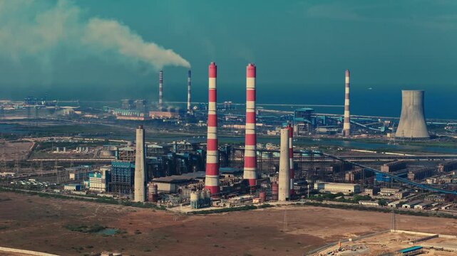 Aerial view of coastal thermal power plant featuring smokestacks cooling tower industrial facilities and power infrastructure beside sea near Chennai.
