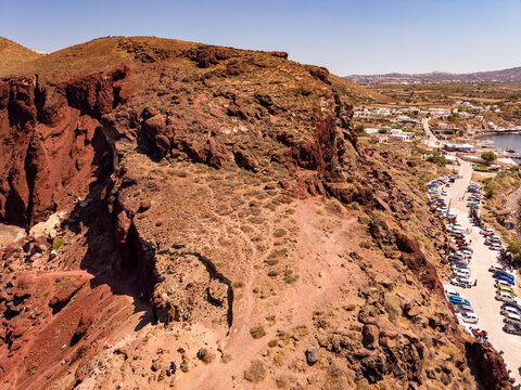 Aerial view of red volcanic cliff and parking area near Red Beach in Santorini Greece drone shot