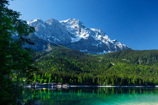 Travel landscape of Zugspitze Alps in Bavaria, Germany, scenic summer nature panorama with forest, Eibsee lake, snow mountains peak. Alpine landscape