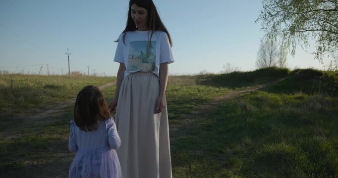 Young mother with child daughter spend time playing enjoying nature. 4K 10-bit