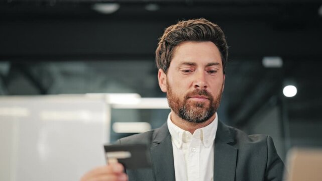 Business professional holding credit card. Concentrating on details for an online purchase or banking transaction. Depicts financial planning, e-commerce, and secure payments in office setting.