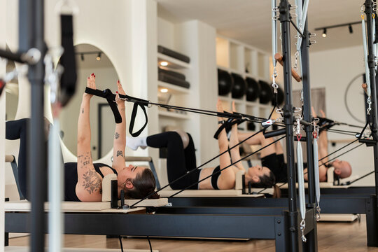 Women training pilates using reformers in modern studio