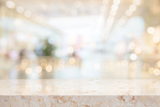 Beautiful texture empty marble table top for your design on deeply blurred interior background illuminated with holiday lights