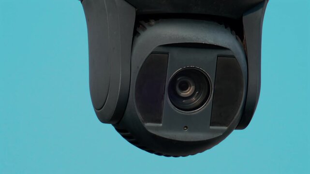 Security camera panning across blue sky background in close up view.
