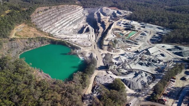 Aerial view of Holcim Australia - Petrie Quarry showing the open-pit mine with a turquoise water-filled basin and industrial infrastructure in Kurwongbah, Queensland, Australia.
