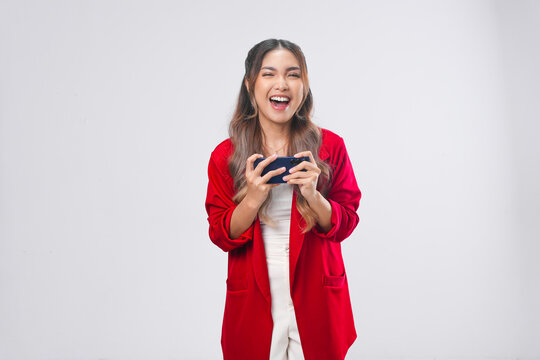 Beautiful young Asian woman in a red jacket is using smartphone playing online games.