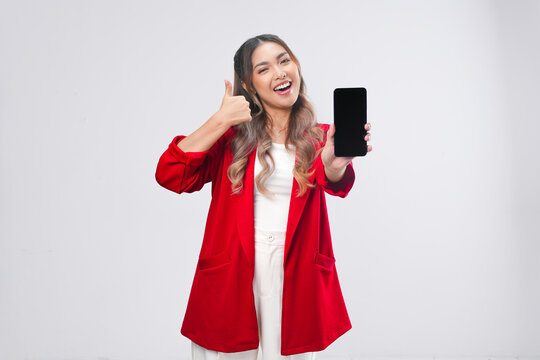 Attractive Asian woman gives thumb up hand gesture while showing copy space on her phone.