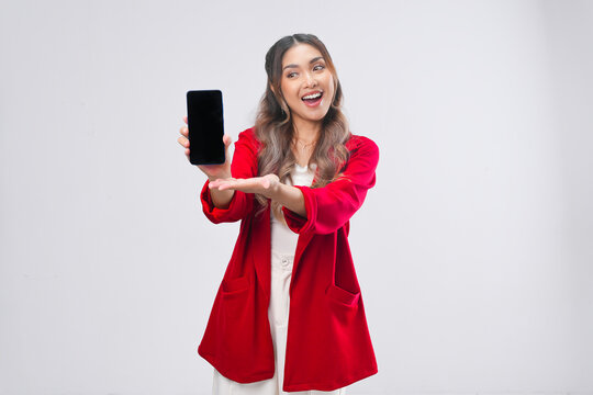 Beautiful young Asian woman in red jacket smiling while showing the copy space on phone screen.