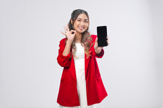 Beautiful young Asian woman in red jacket smiling while showing the copy space on phone screen.