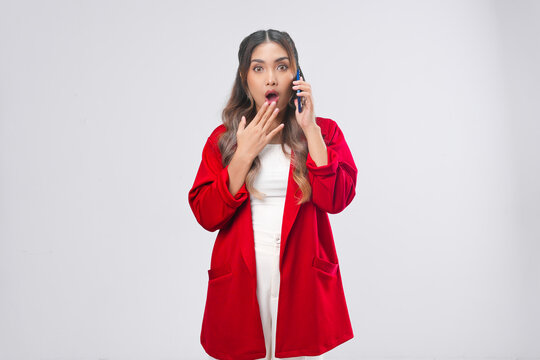 Shocked young Asian woman in red jacket using her smartphone calling someone.