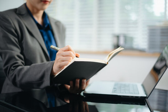 Close-up view of young professional businesswoman writing his idea concepts on notebook while working on his project at office