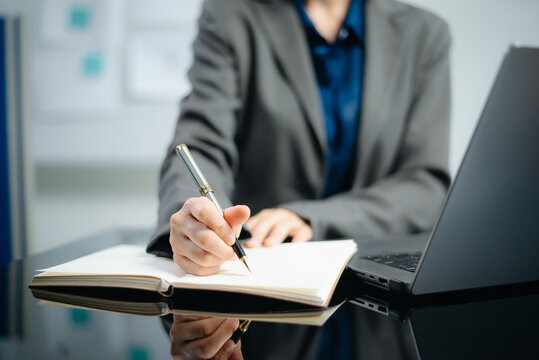 Close-up view of young professional businesswoman writing his idea concepts on notebook while working on his project at office