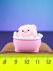 Close-up of a cute miniature pig figurine with bath accessories on a vibrant purple background. Adorable decorative ornament with playful details, perfect for home decor, crafts and collections. © Виталий Сова