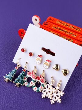 Close-up of a set of Christmas earrings featuring snowflakes, Christmas trees, Santa Claus, and other festive designs