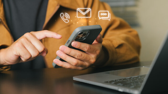 Person Using Smartphone with Communication Icons Above in Office Setting