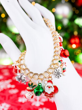 Close-up of a metallic Christmas bracelet with pendants in the shape of Santa Claus, a bell, snowflake, and other festive charms