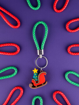 Close-up of a Christmas sleigh with a decorated tree keychain on a vibrant purple background. Festive holiday accessory
