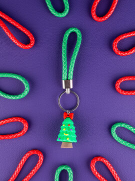 Close-up of a Christmas tree keychain on a vibrant purple background. Festive holiday accessory with seasonal details, perfect for keys, bags, Christmas gifts, winter decorations and celebrations.