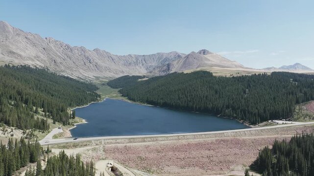 Aerial view of Clinton Gulch Dam Reservoir surrounded by dense pine forests and rugged mountains in Summit County, Colorado, United States.