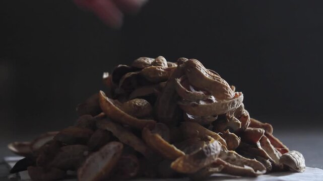 Close-up of hands eating peanuts and discarding shells, capturing a casual snack moment at home now.
