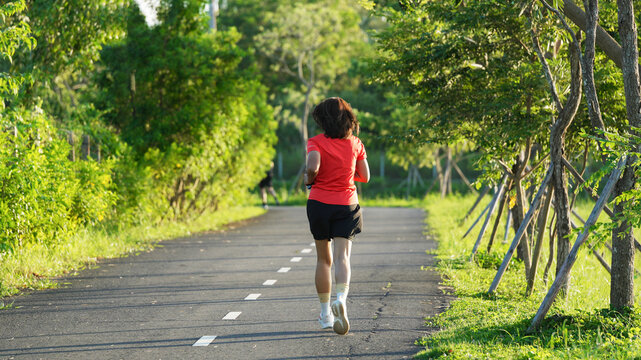 Woman Running on a Scenic Road Surrounded by Green Trees and Nature