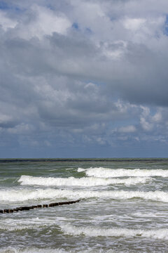 Foamy white sea waves crashing onto cadzand beach under dramatic cloudy skies along the north sea coast