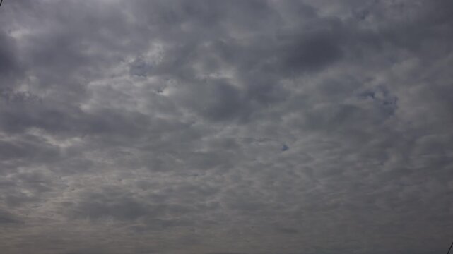 Cinematic time-lapse of dramatic gray stratocumulus clouds moving across the sky. Dense overcast cloudscape creates a moody atmospheric background, perfect for weather, climate, nature, forecast