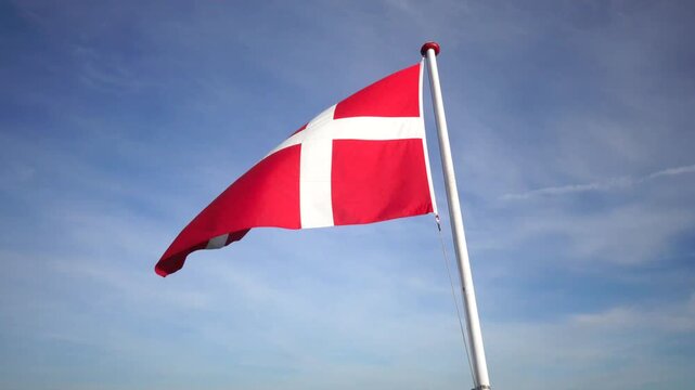 Hirtshals, Denmark A large Danish flag or Dannebrog flies in the wind on a flagpole. 